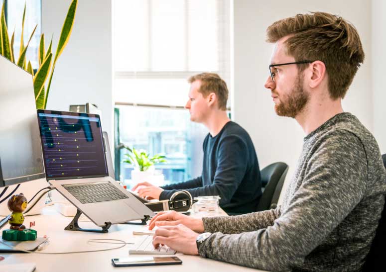 Two men sitting front of laptop and engaged in work